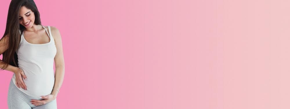 pregnant women smiling in front of pink background