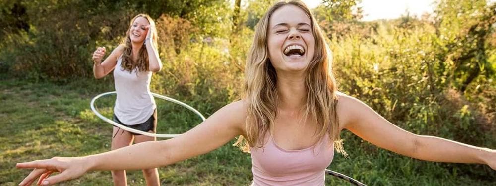 two girls hula hooping and smiling
